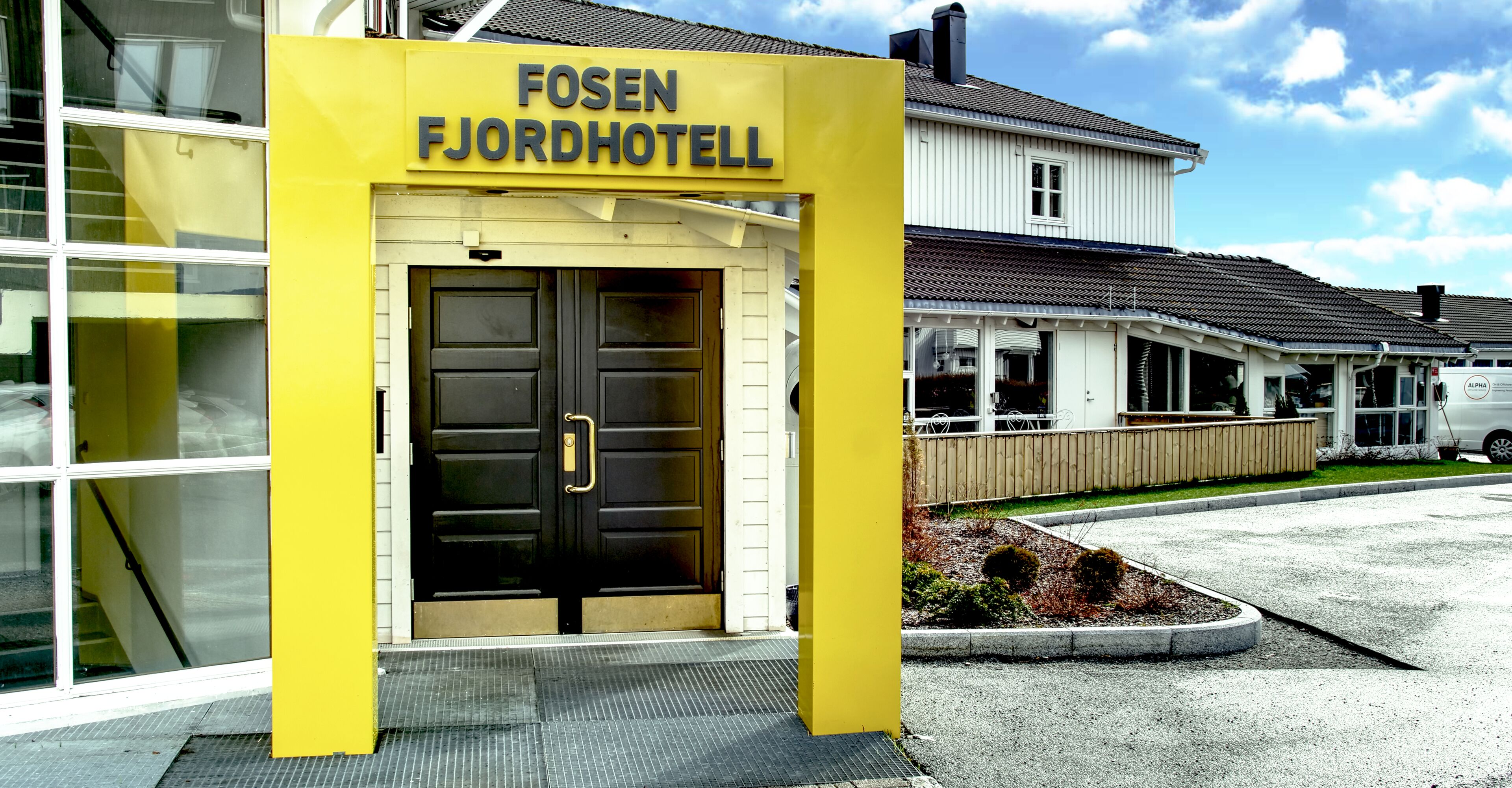 A hotel entrance with a yellow sign reading "FOSEN FJORDHOTELL".