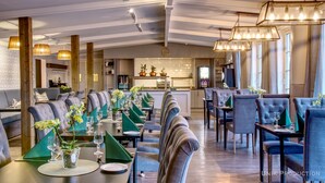 Een restaurant met een lange eetzalen, hoge plafonds en moderne verlichtingsarmaturen.