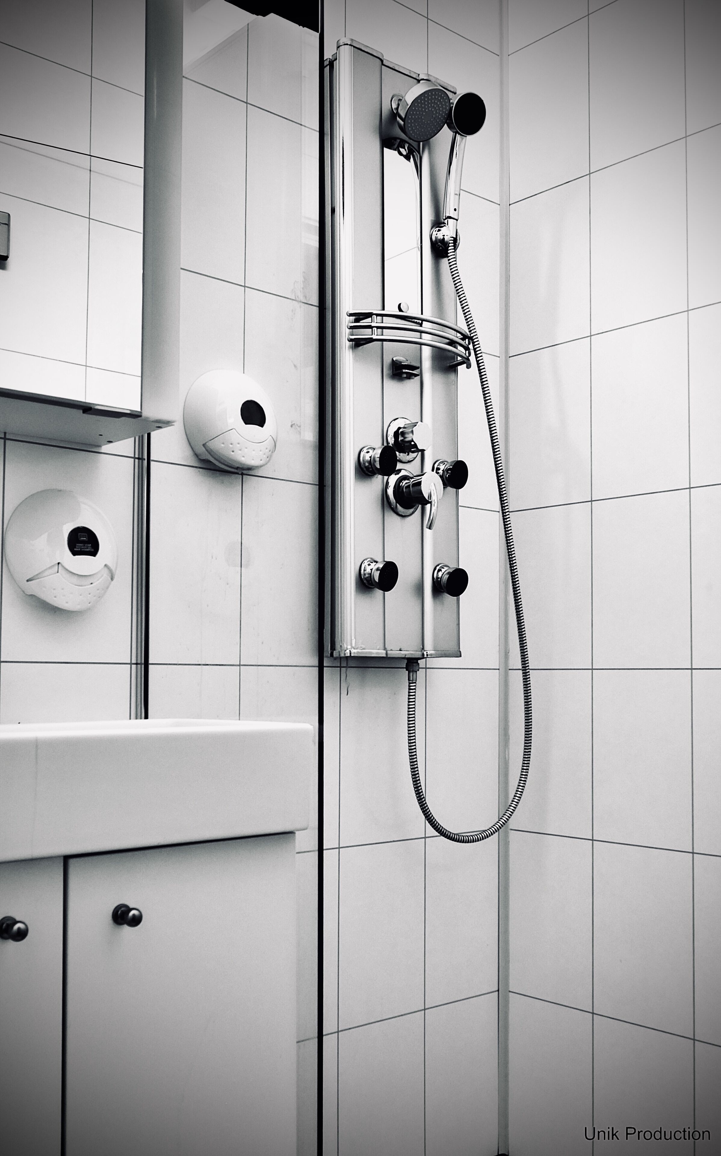 A modern bathroom with a shower, a soap dispenser, and a towel rack.