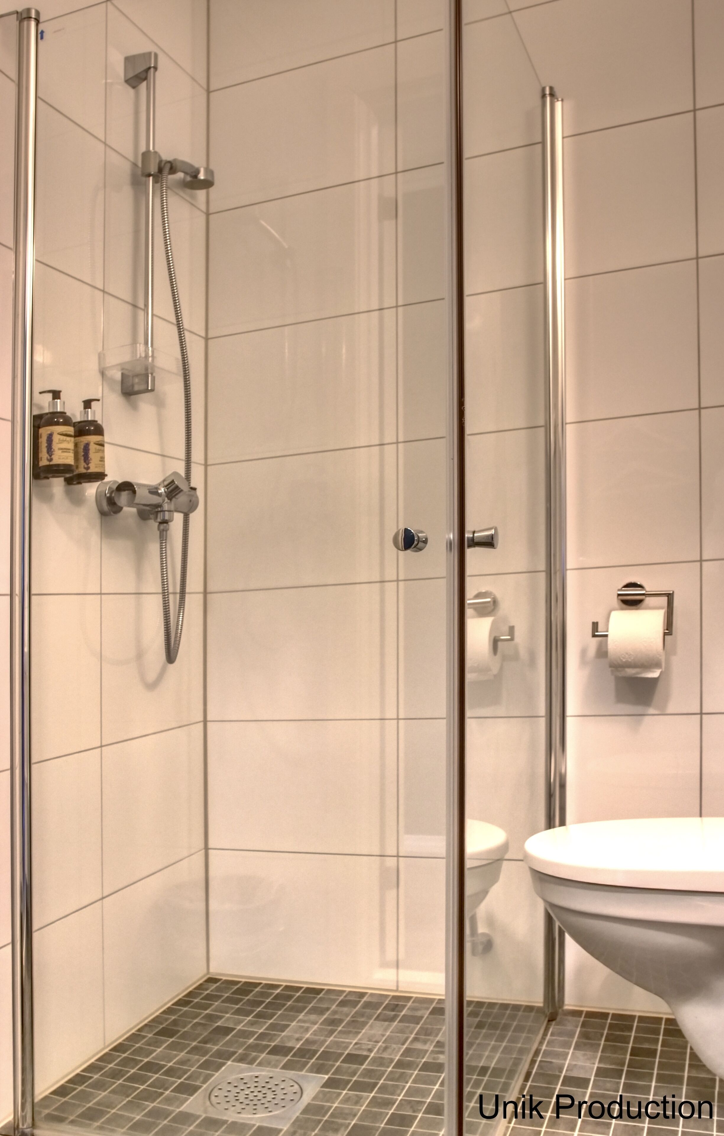Un baño moderno con ducha de mampara de vidrio, inodoro y lavamanos.