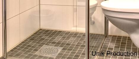 Un baño moderno con ducha de mampara de vidrio, inodoro y lavamanos.