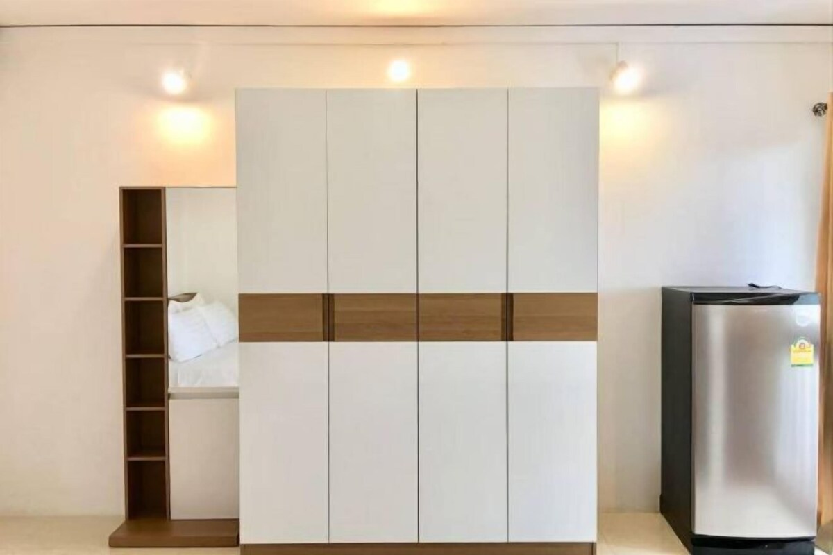 Una habitación moderna con armario, estante empotrado y refrigerador.