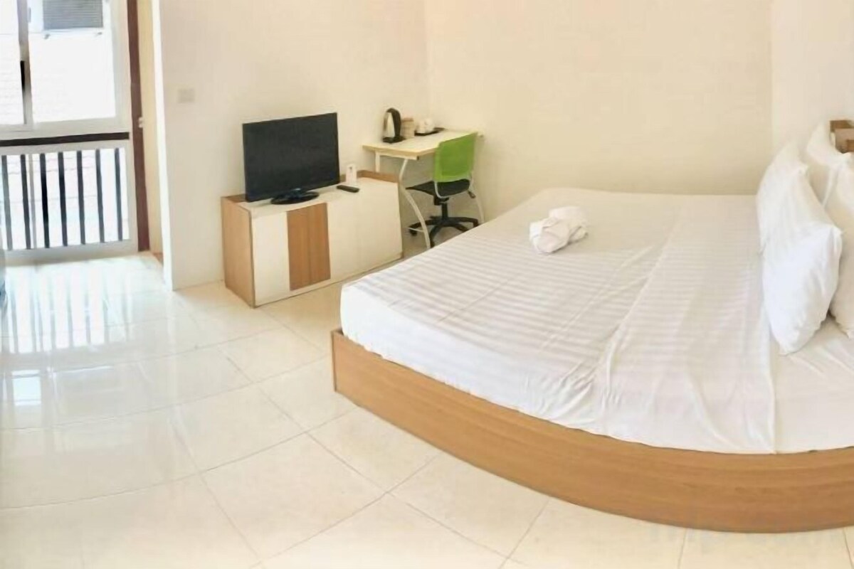 Une chambre d’hôtel avec un lit, une télévision, un bureau et une chaise.