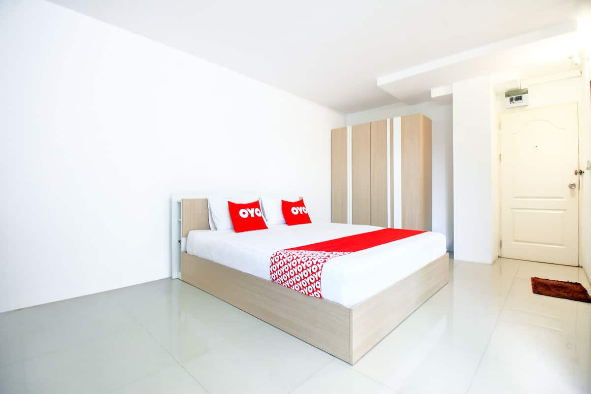 Ein modernes Schlafzimmer mit Bett, weißen Wänden und einem Holzschrank.