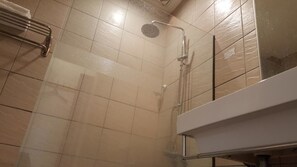 A shower with a handheld showerhead and a wall-mounted faucet.