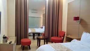 A hotel room with a bed, a desk with a coffee maker, a chair, a small table, and a window with curtains. - Yang Homestay (Ruisui)