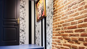 A staircase with blue steps leading to a door with a black and white floral wallpaper. A framed picture hangs on the wall above the staircase. - Manoir des Lions de Tourgéville (Tourgeville)