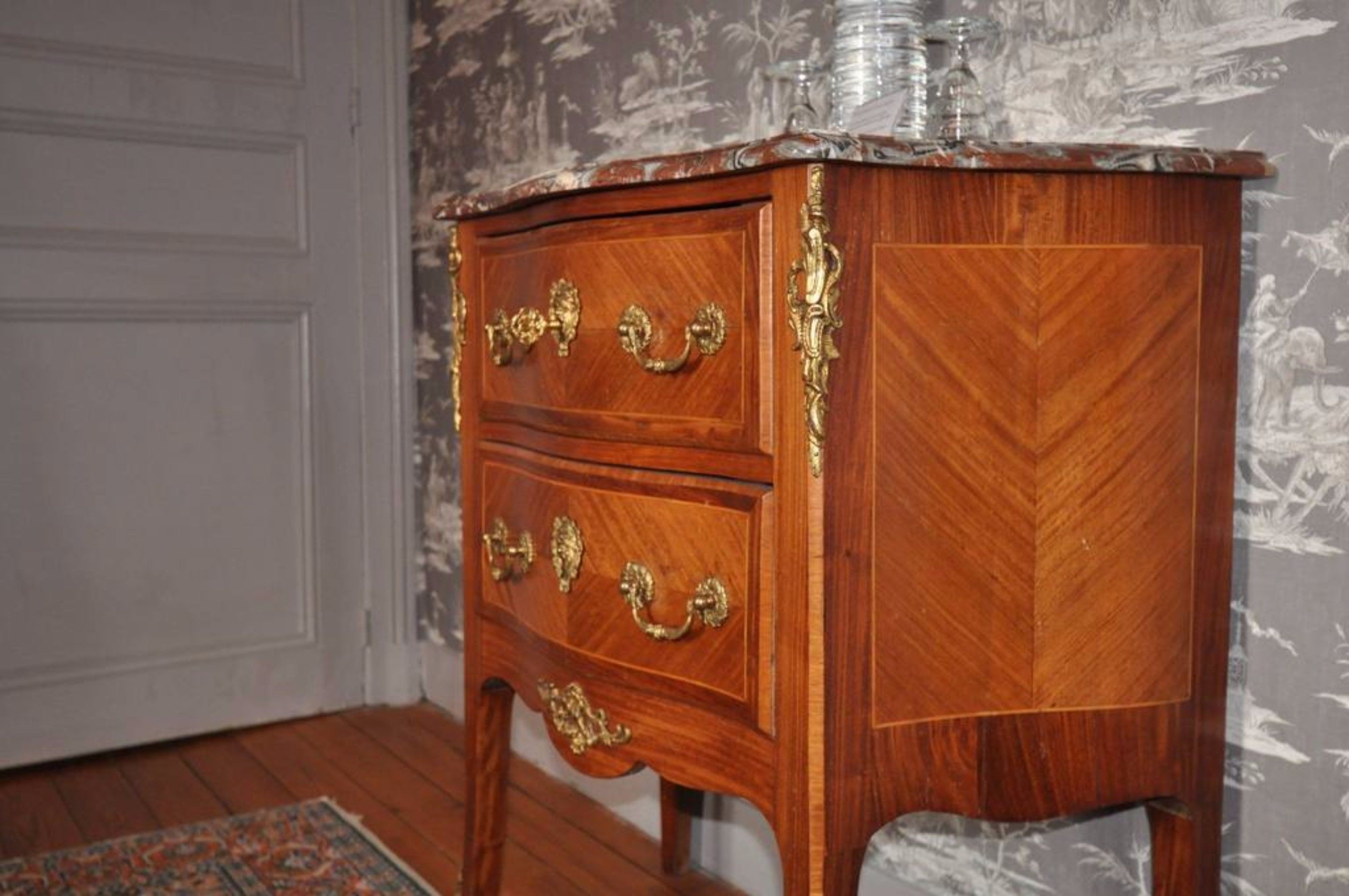 A wooden cabinet with ornate gold handles and a decorative top.
