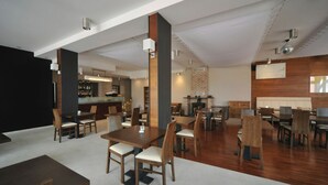 A spacious restaurant with high ceilings, wooden tables and chairs, a brick fireplace, and a bar area. - Vertigo Narie (Morag)