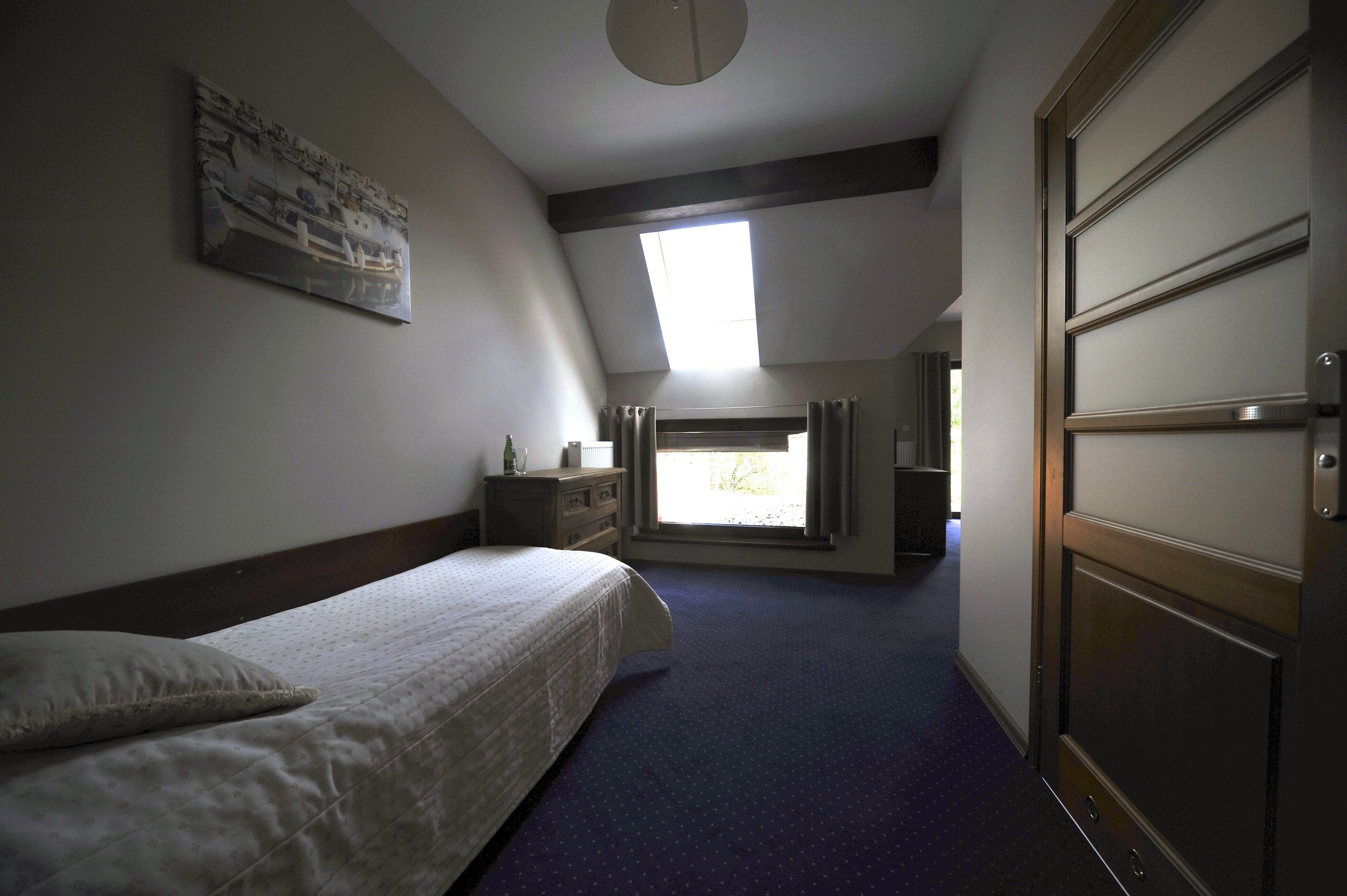 A bedroom with a bed, a dresser, a window, and a door.