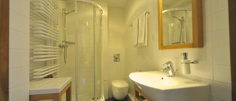 A bathroom with a glass-enclosed shower, a white sink, and a toilet.