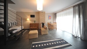 A modern hotel room with a staircase, a fireplace, a dining area, and a large window with curtains. - Vertigo Narie (Morag)