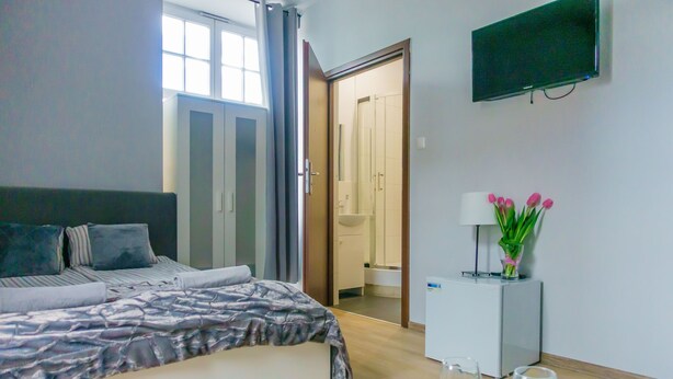 Una habitación de hotel moderna con una cama, un televisor, una pequeña mesa con vasos y una puerta que da a un baño.