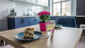 Una mesa de comedor con una rebanada de pastel, un vaso de agua y una planta en una maceta rosa.