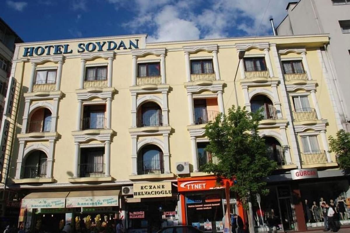 A hotel with a classic facade, multiple balconies, and a ground-level shop.