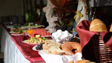 Uma mesa de buffet com diversos alimentos e uma toalha vermelha.