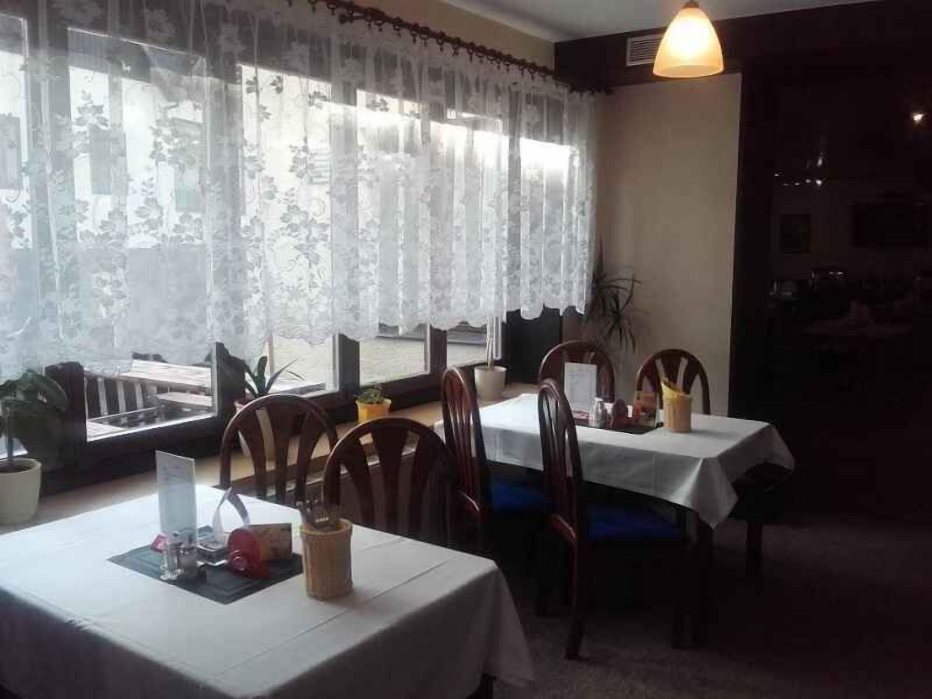 A dining area with tables set for two, covered with white tablecloths, and chairs with blue cushions.