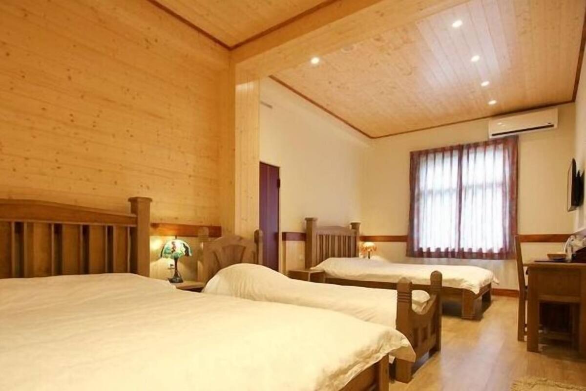 A room with two wooden beds, a desk, a chair, and a window with curtains.