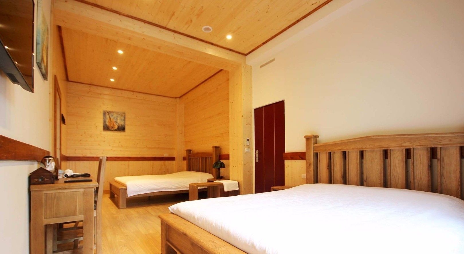 A wooden room with two beds, a desk, and a chair.