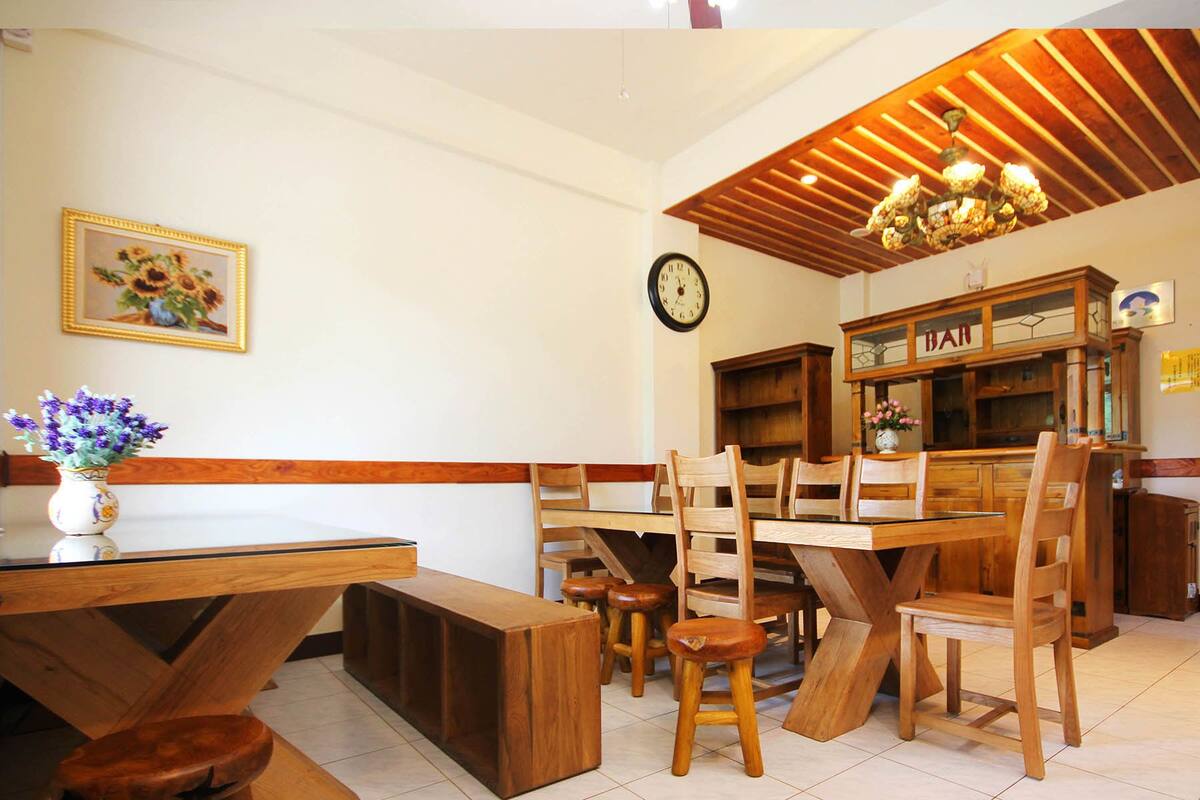 A dining area with wooden furniture, a clock, and a 'BAR' sign.
