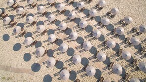Vue aérienne d’une plage avec des rangées de transats et de parasols.