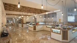 Un vaste espace buffet doté de plusieurs points de service, d’un sol en marbre poli et de poutres en bois apparentes au plafond.