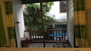 A room with a bed, a small desk, and a view of a balcony with a chair and a table. - Lucky Guesthouse (Ko Phi Phi)