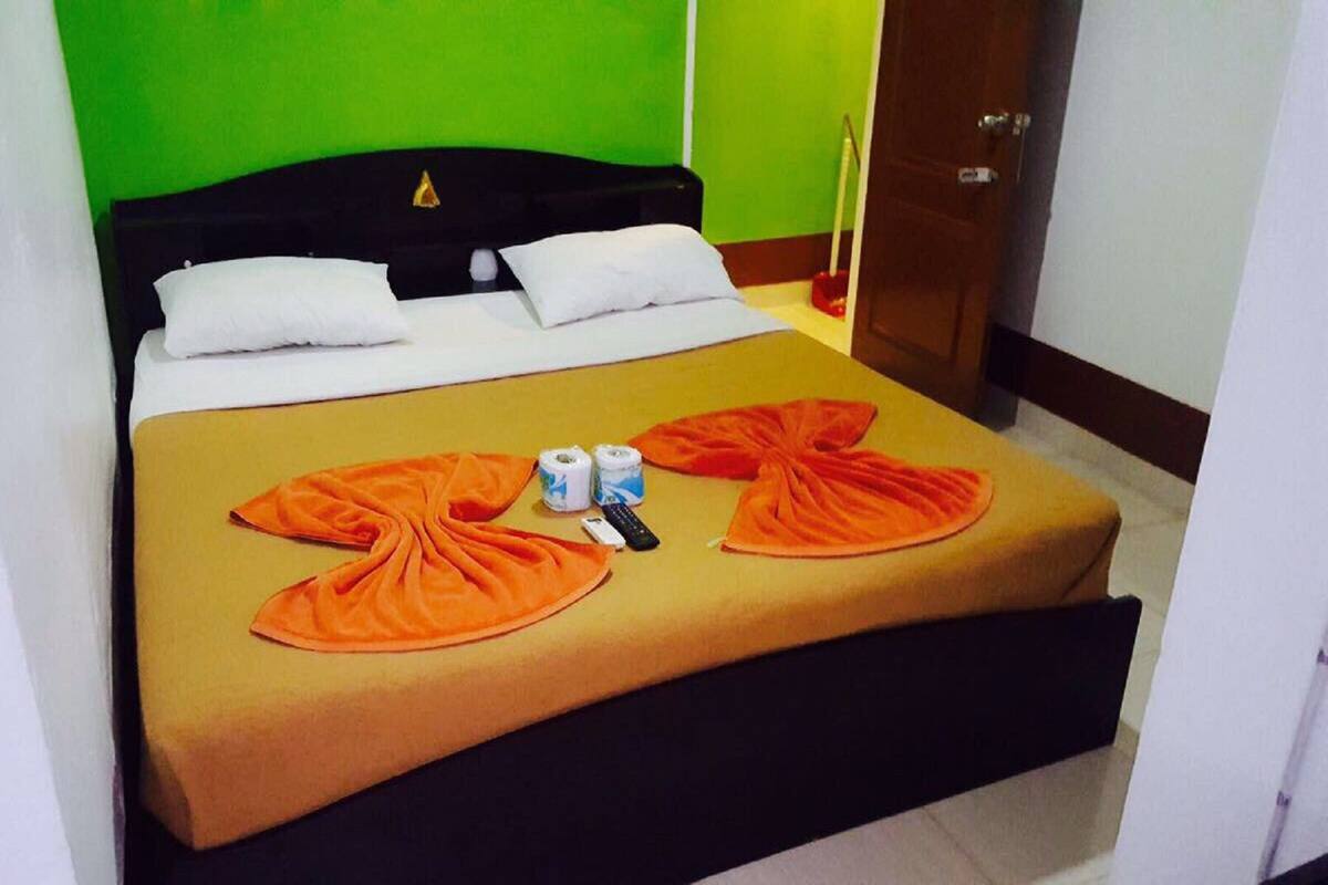Ein Hotelzimmer mit einem Bett, Kissen, einer Decke, einer Fernbedienung und zwei Dosen auf dem Bett.