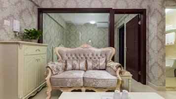 A room with a tufted sofa, a cabinet, and a table with a vase and a glass object.