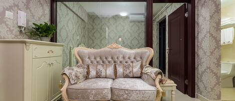 A room with a tufted sofa, a cabinet, and a table with a vase and a glass object.