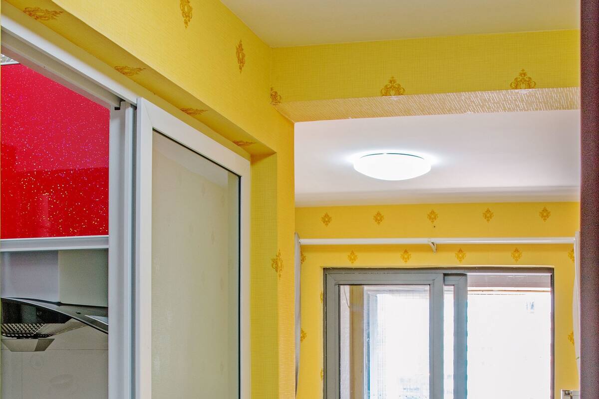 Un soggiorno luminoso con una porta-finestra che si apre su un balcone, un divano bianco e un tavolino da caffè.
