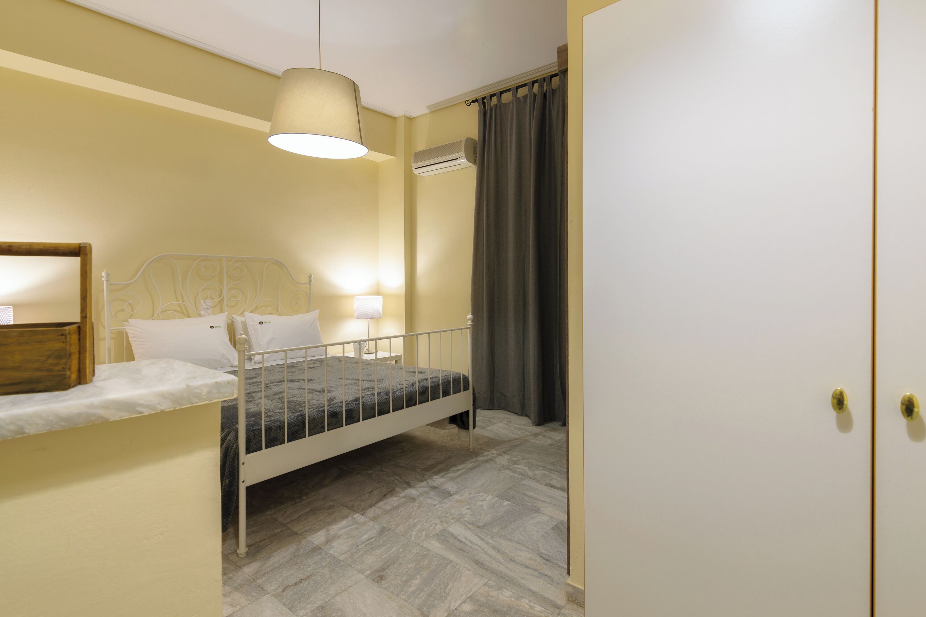 Un dormitorio con cama, mesita de noche, lámpara y aire acondicionado.