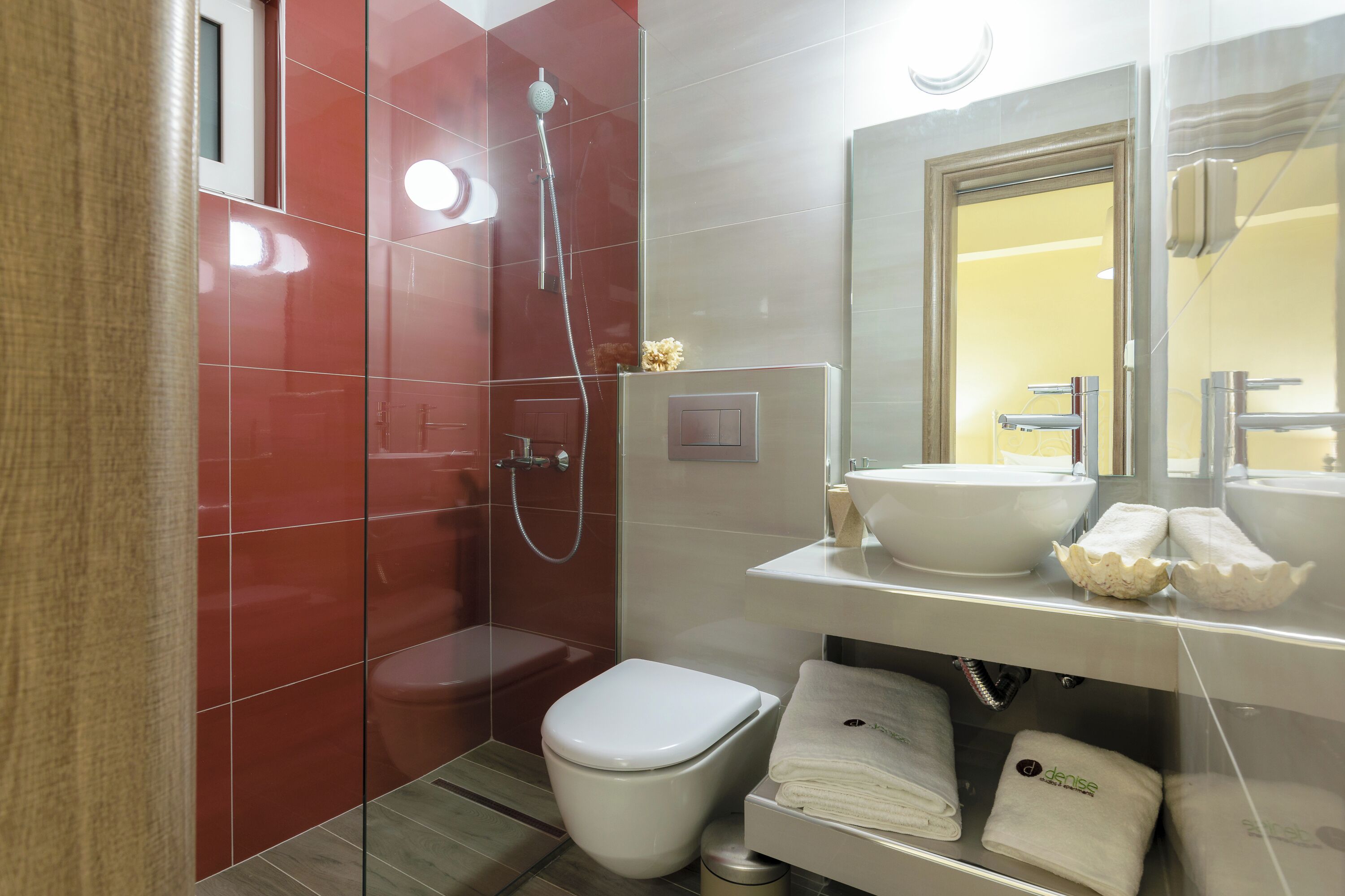 A modern bathroom with a glass shower enclosure, a white toilet, and a sink with a mirror above.
