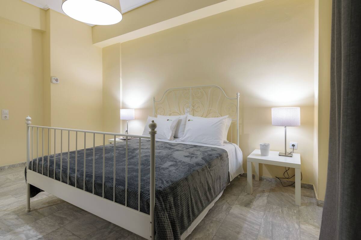 A bedroom with a bed, bedside tables, and a lamp.
