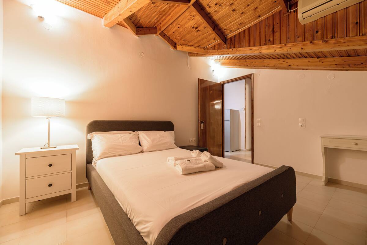 A bedroom with a bed, bedside table, and a desk.