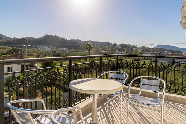 A balcony with a metal railing, a round table, and two chairs.