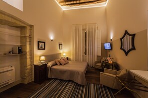 A hotel room with a bed, a desk, a chair, a TV, a lamp, and a mirror. - Il Regio Boutique Hotel (Cagliari)