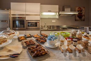 A kitchen with stainless steel appliances, a variety of baked goods, and condiments on the counter. - Il Regio Boutique Hotel (Cagliari)