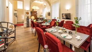A dining area with red upholstered chairs, a round table set for four, and a wooden ceiling.