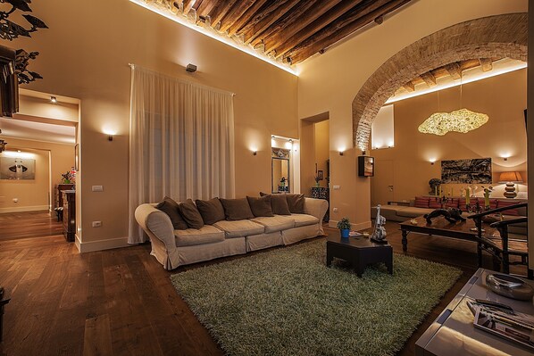 A spacious living room with a large sofa, a coffee table, and a fireplace. - Il Regio Boutique Hotel (Cagliari)