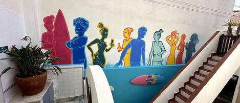 A staircase with a colorful mural on the wall, a potted plant, and a sign indicating room number 101.