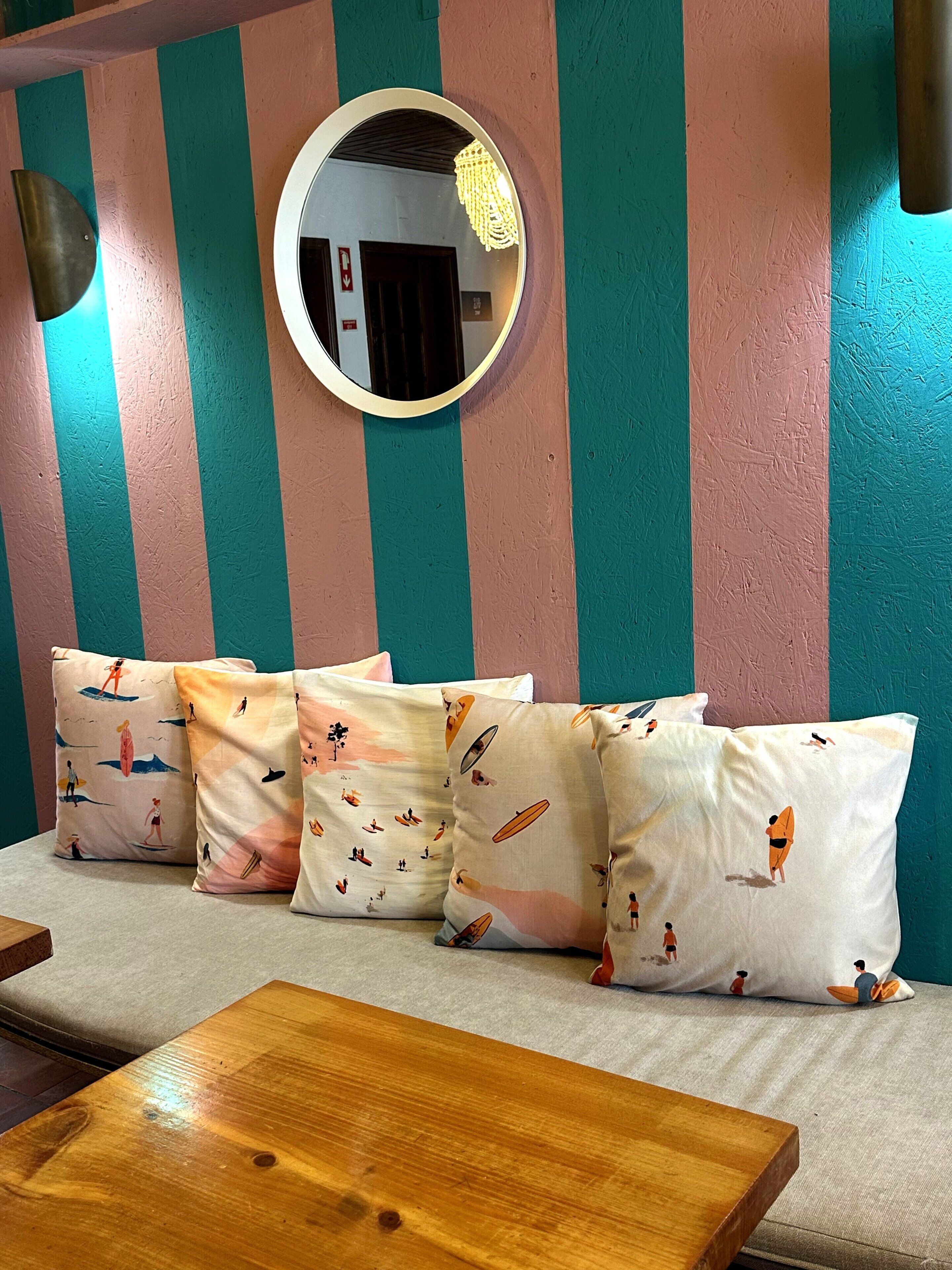A room with striped walls, a round mirror, and patterned cushions on a sofa.