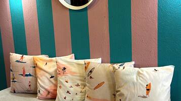 A room with striped walls, a round mirror, and patterned cushions on a sofa.