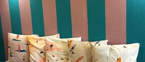 A room with striped walls, a round mirror, and patterned cushions on a sofa.