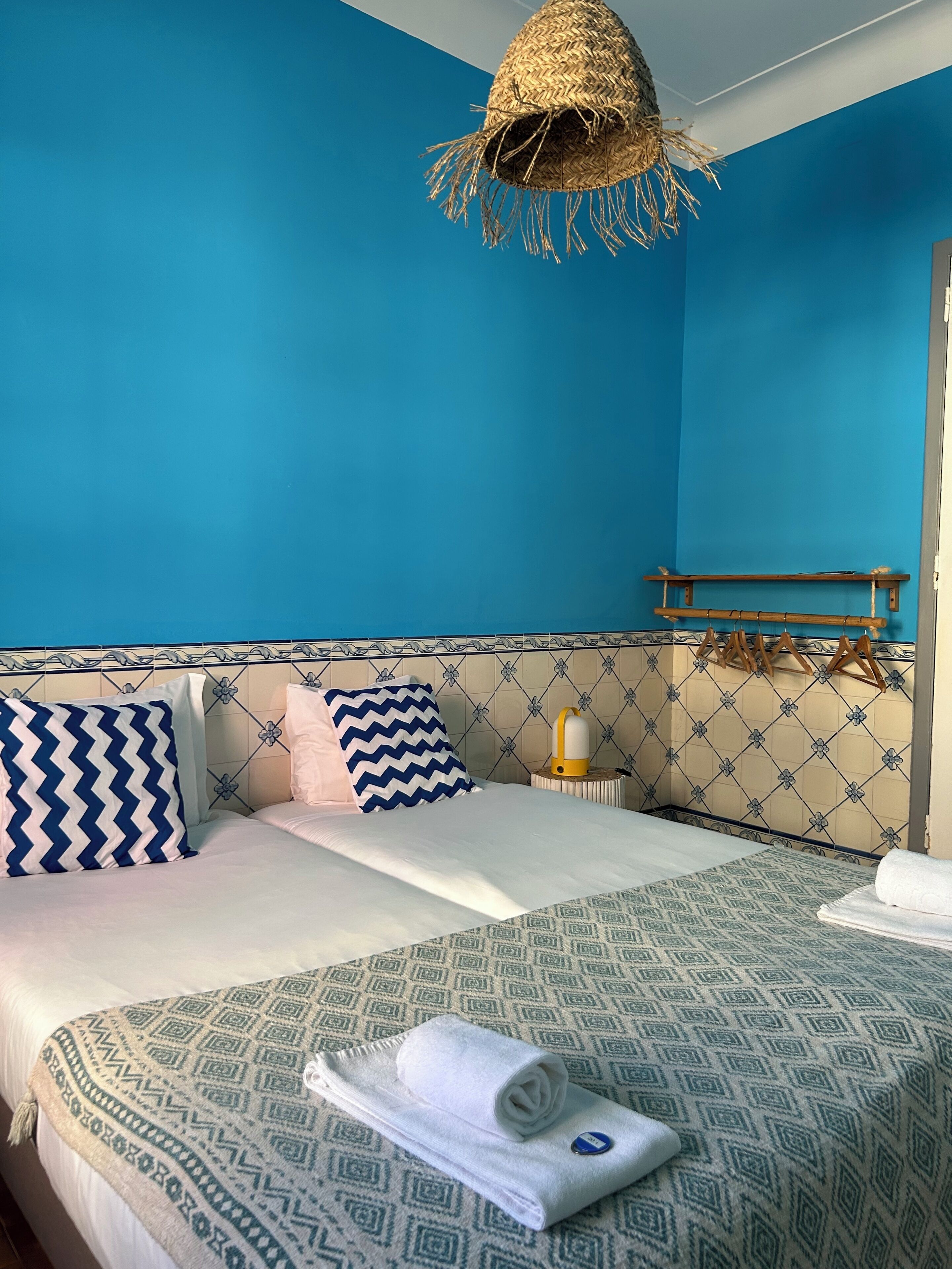 Una habitación de hotel con cama, mesita de noche, lámpara y una lámpara colgante.
