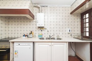 Una cocina equipada con lavavajillas, pileta doble y calentador de agua.