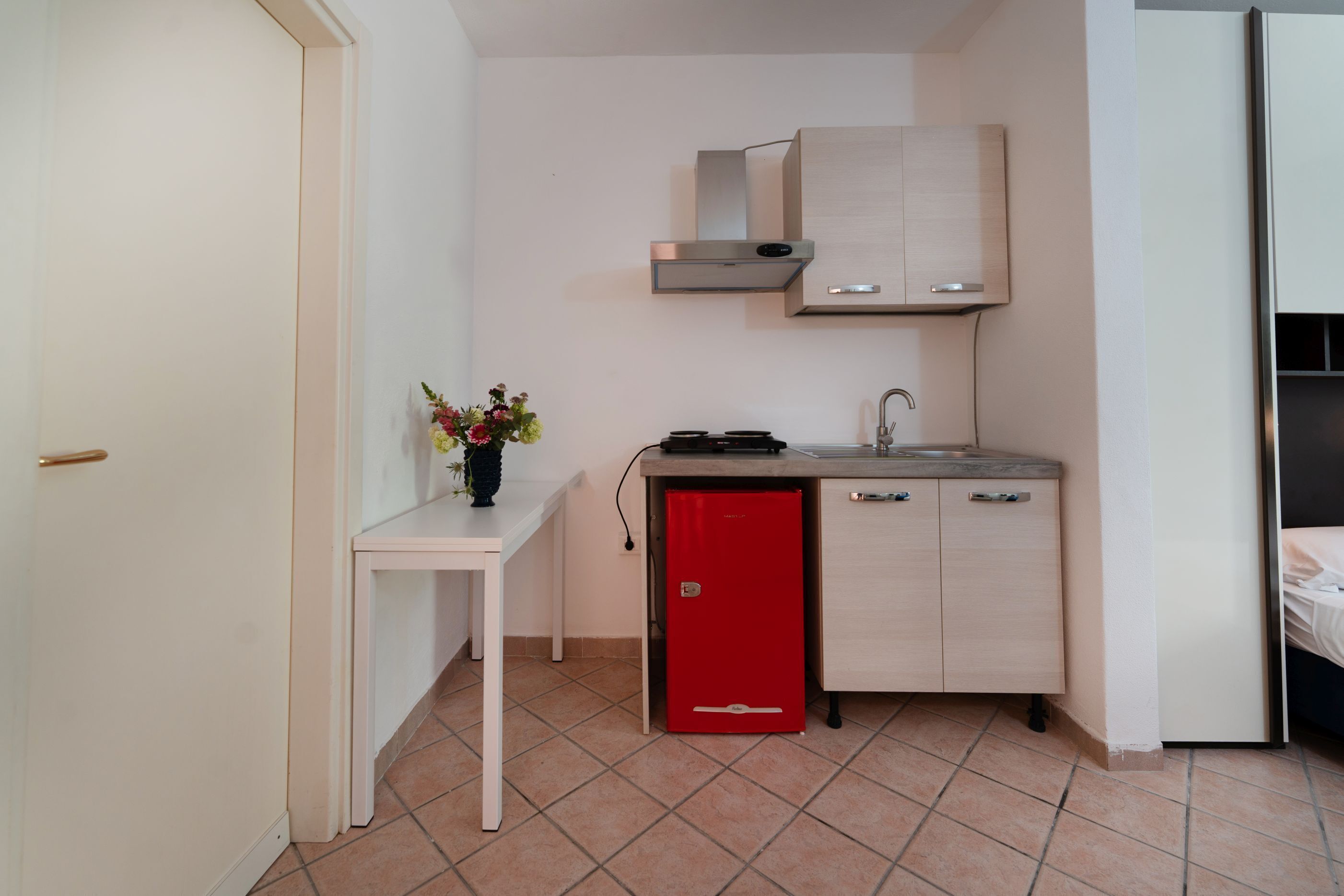 A compact kitchen with a red refrigerator, a sink, and a countertop.