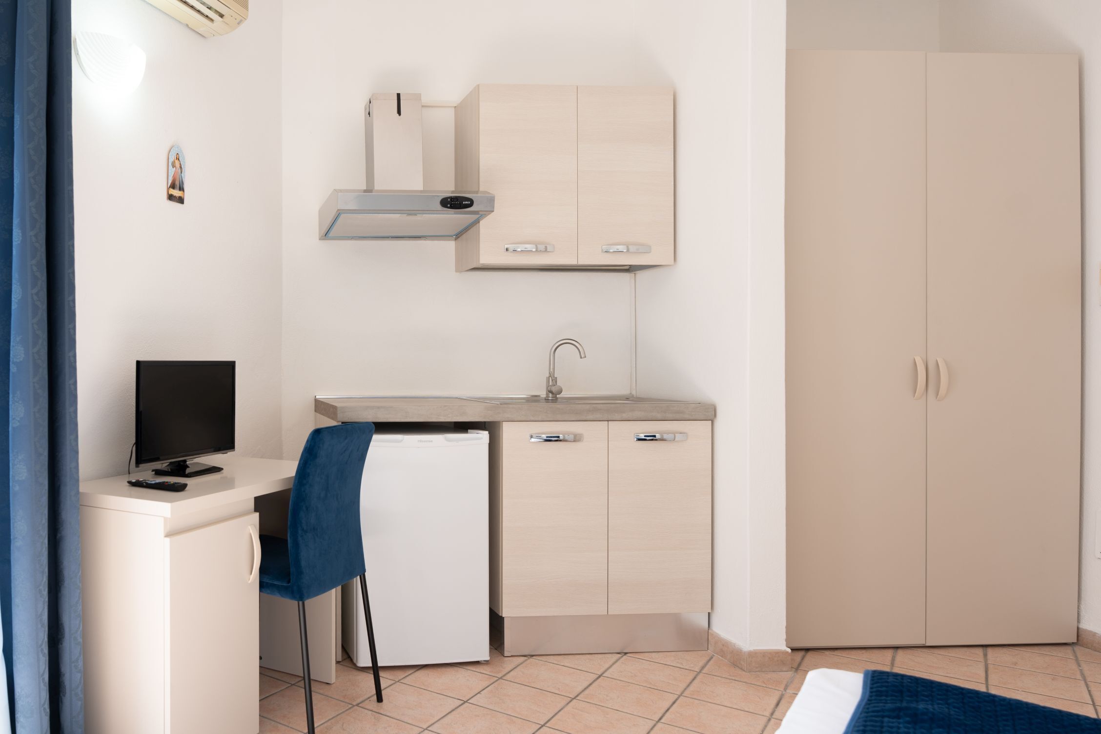 Een kleine keuken met een inbouwfornuis, een kleine koelkast en een spoelbak.