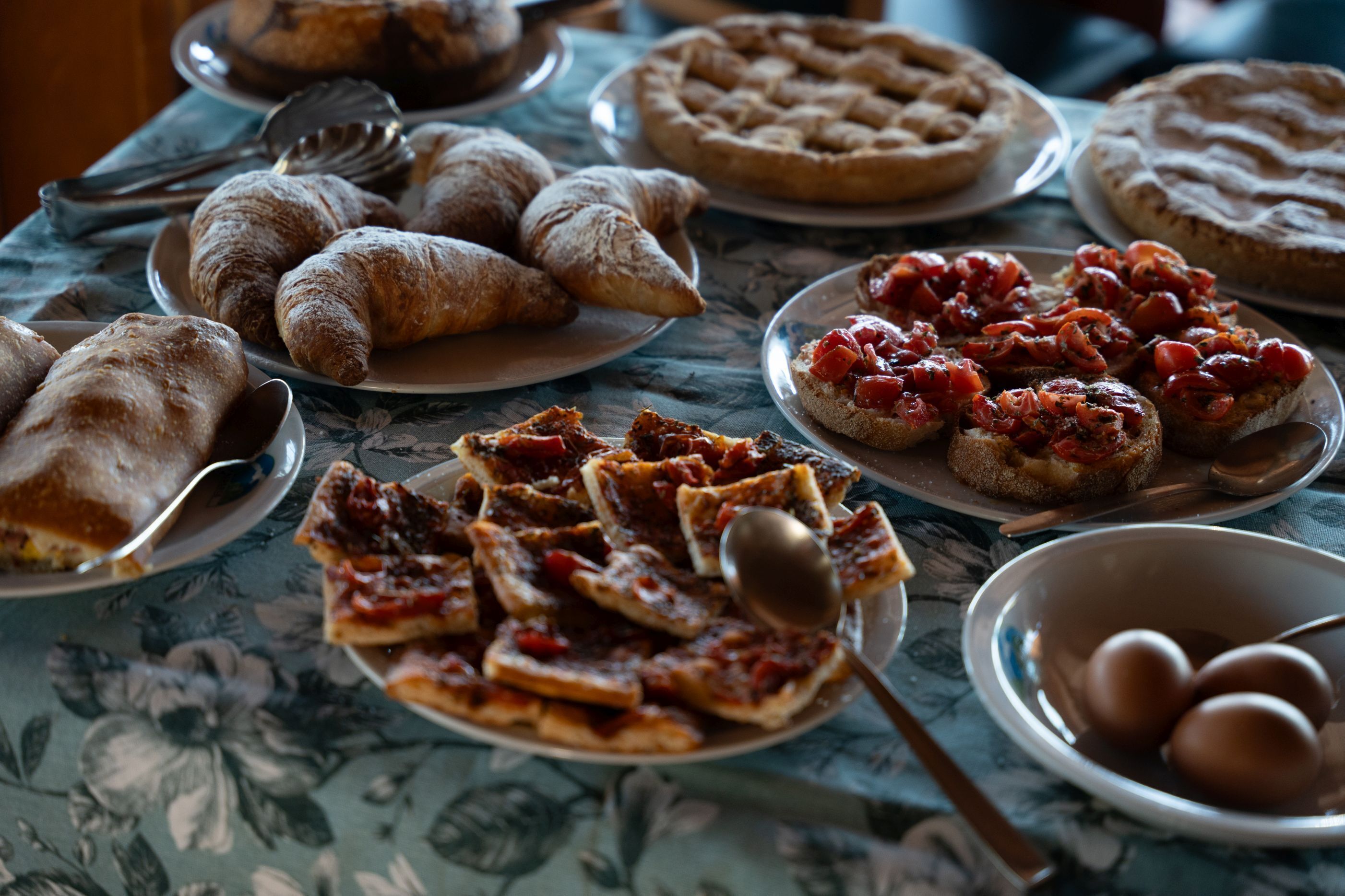 Una mesa con diferentes alimentos, incluyendo pasteles, pizza y pan.