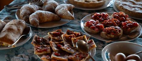 Una mesa con diferentes alimentos, incluyendo pasteles, pizza y pan.